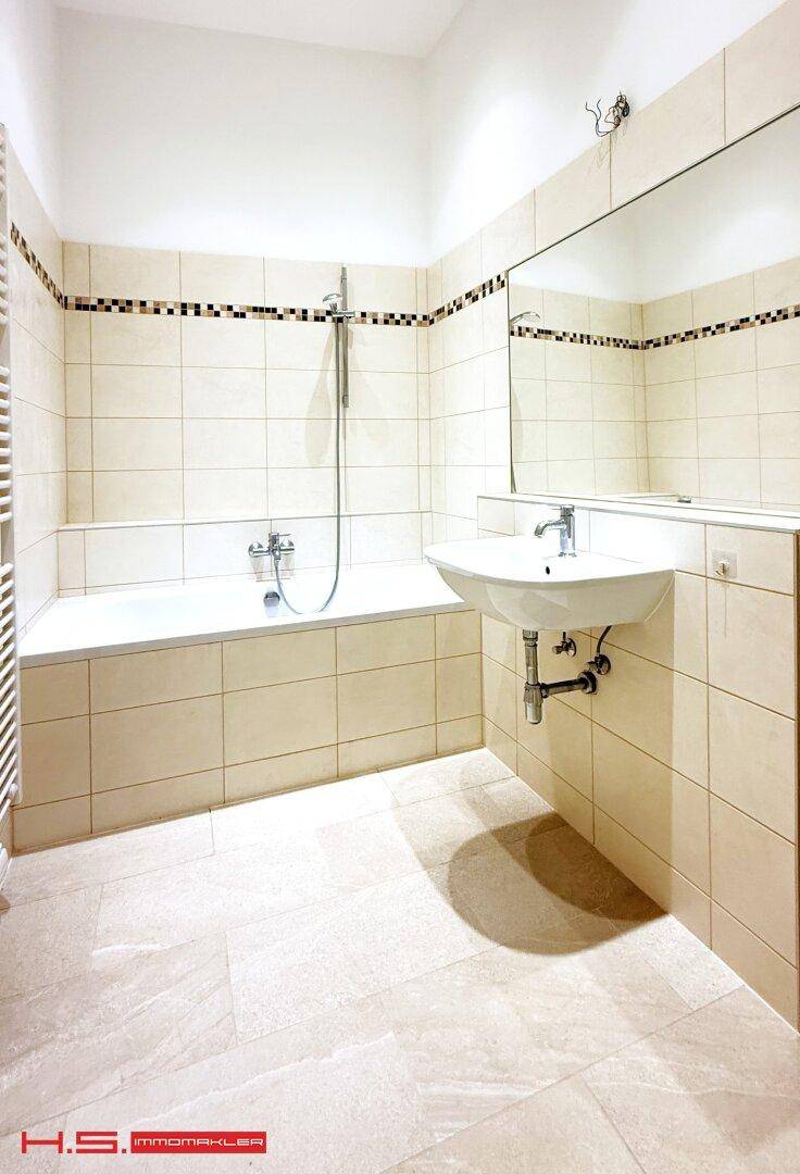 Modernes Badezimmer mit Badewanne, Waschbecken und großformatigen Fliesen.