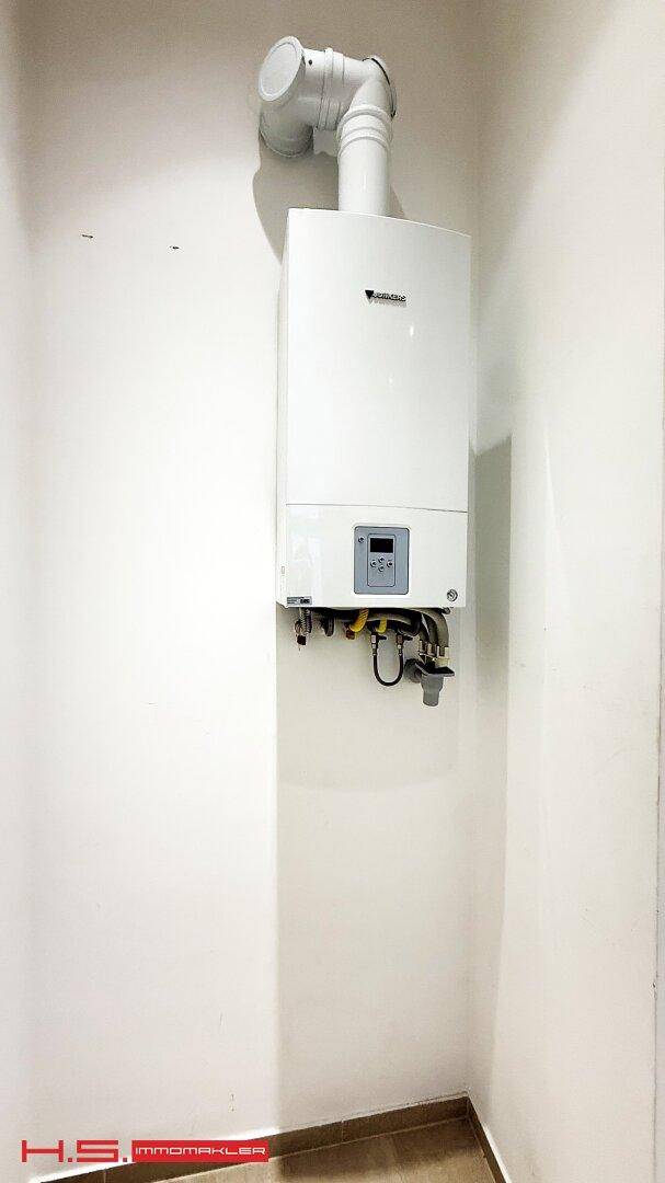 Wandmontierter Gasboiler in einem kleinen Raum, wahrscheinlich ein Hauswirtschaftsraum.