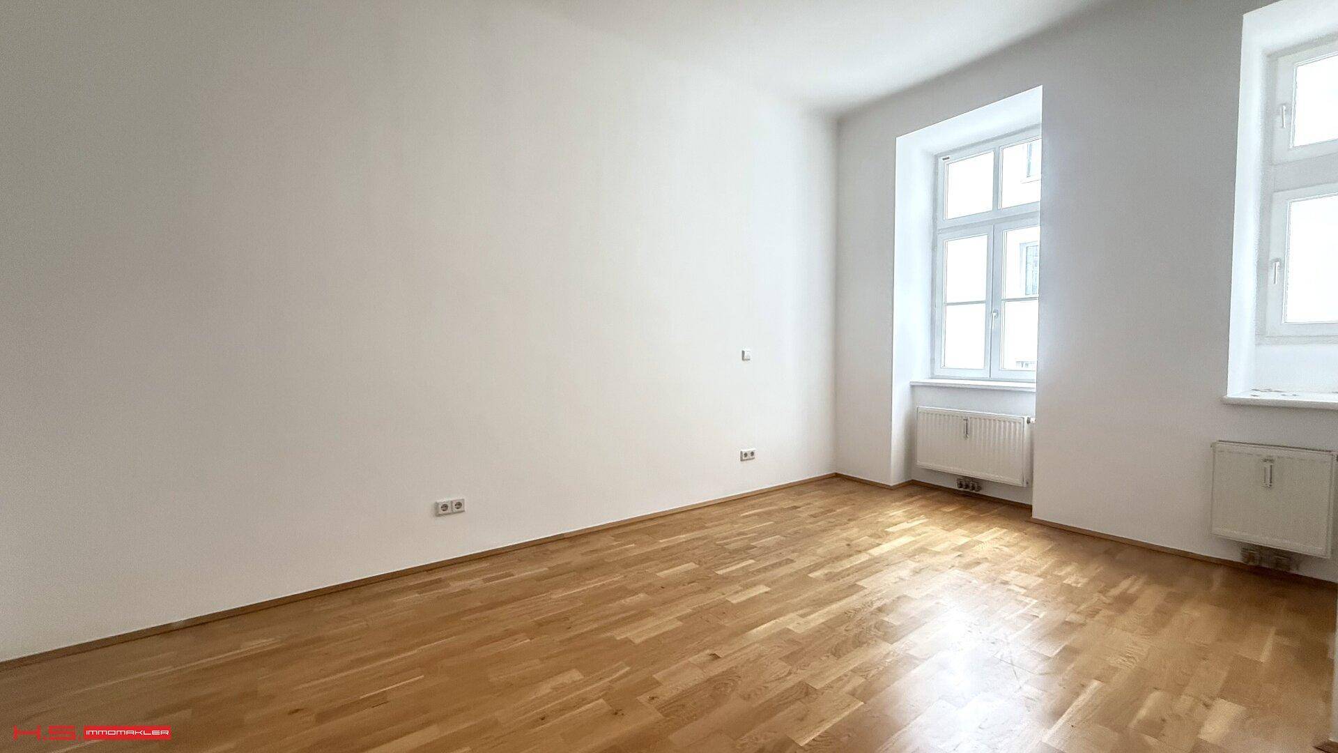 Lichtdurchfluteter Raum mit Parkettboden und weiß gestrichenen Wänden, vielseitig nutzbar.