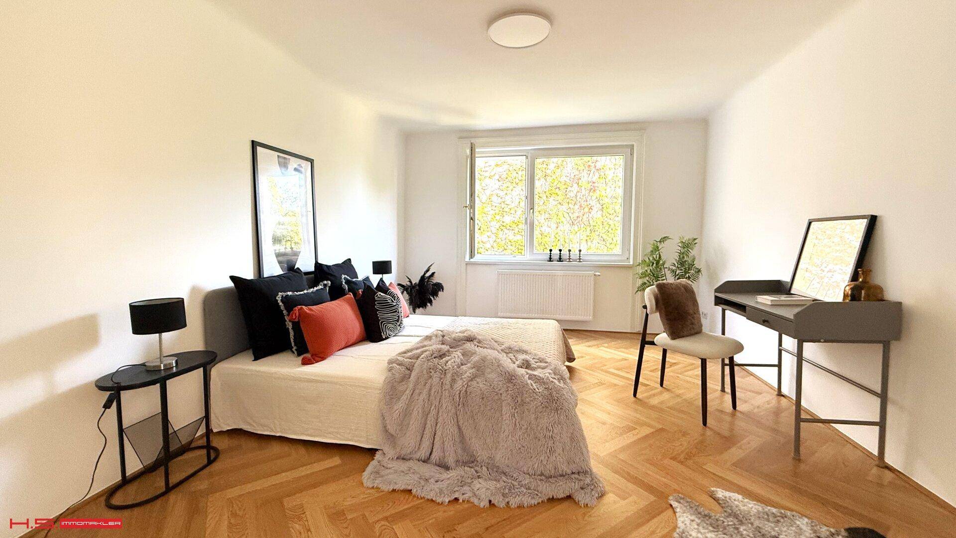 Helles Schlafzimmer mit Doppelbett, Schreibtisch und Blick ins Grüne.