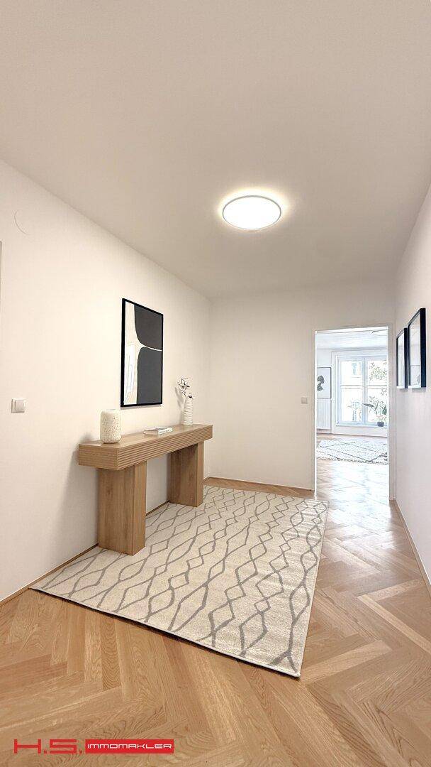 Langer Flur mit stilvoller Holzkonsole und Teppich, der einen Blick in den Wohnbereich freigibt.
