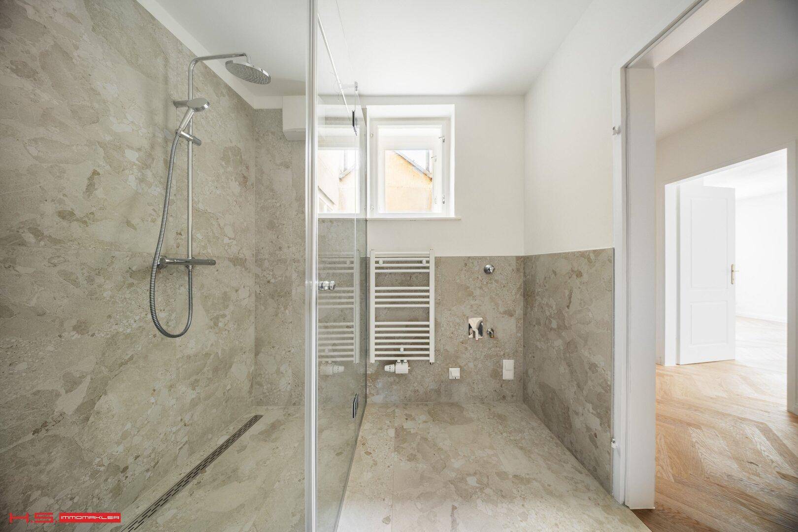 Modernes Badezimmer mit begehbarer Dusche und grauen Fliesen, noch in Fertigstellung.