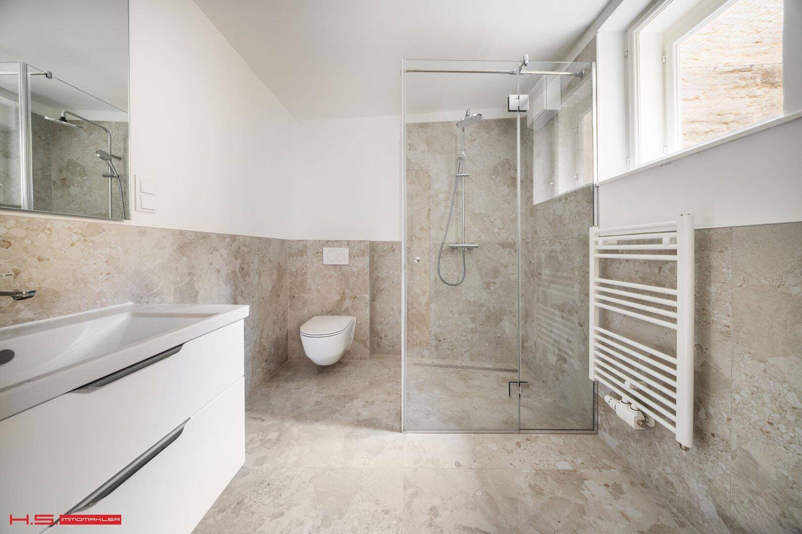 Helles Badezimmer mit moderner begehbarer Dusche, Wand-WC und Heizkörper.