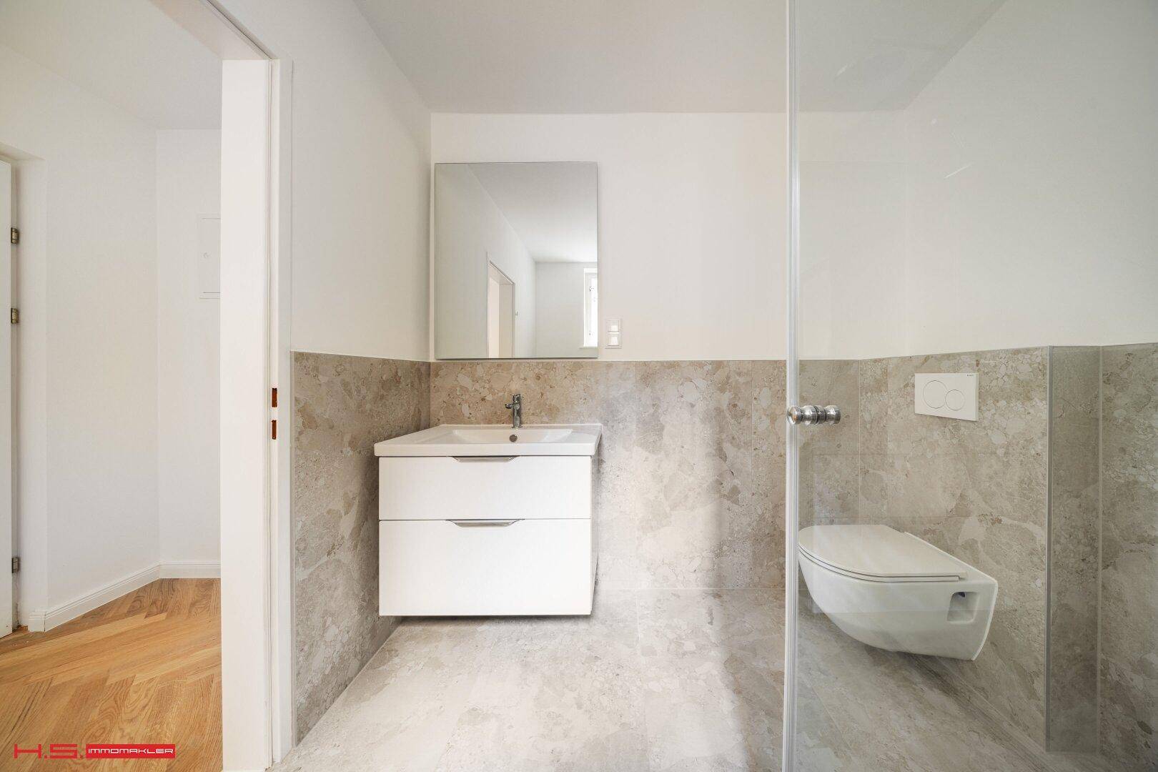 Modernes Badezimmer mit schwebendem Waschtisch, Wand-WC und großem Spiegel.