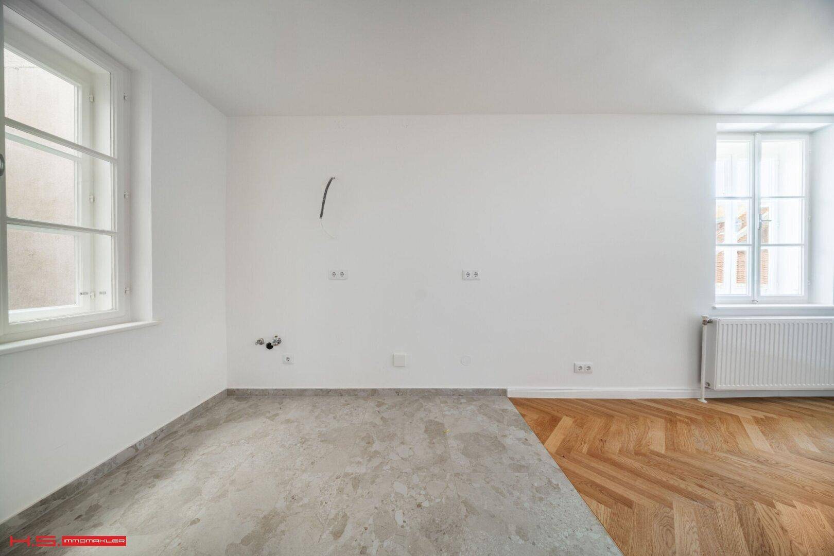 Lichtdurchflutetes Zimmer mit neuem Fischgrätparkett und einem Bereich für weitere Gestaltung.