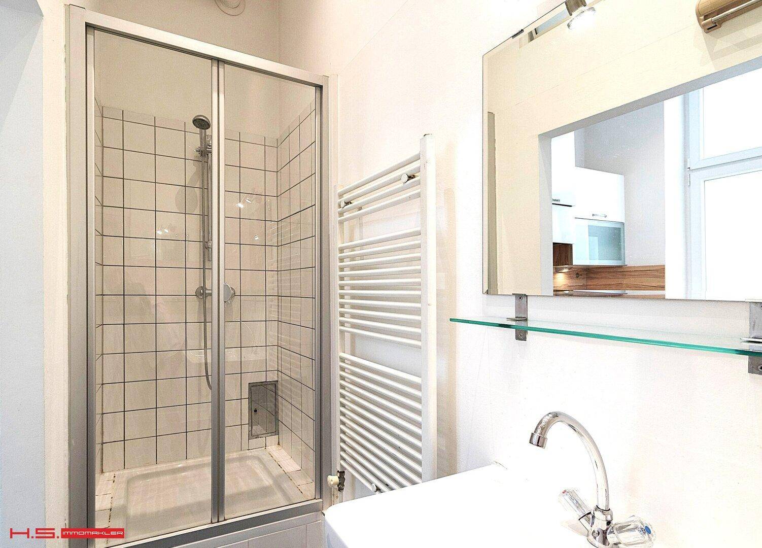 Modernes Badezimmer mit Duschkabine, Waschbecken und beheiztem Handtuchhalter.