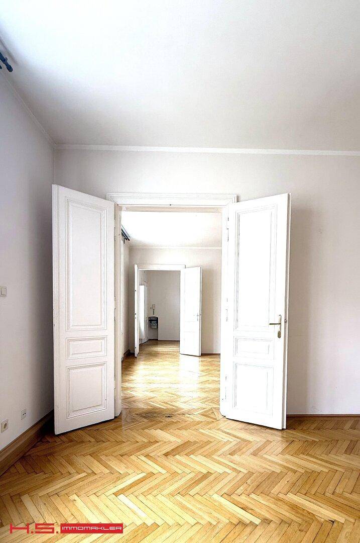 Blick durch mehrere offene Türen in helle Zimmer mit Fischgrätparkett.