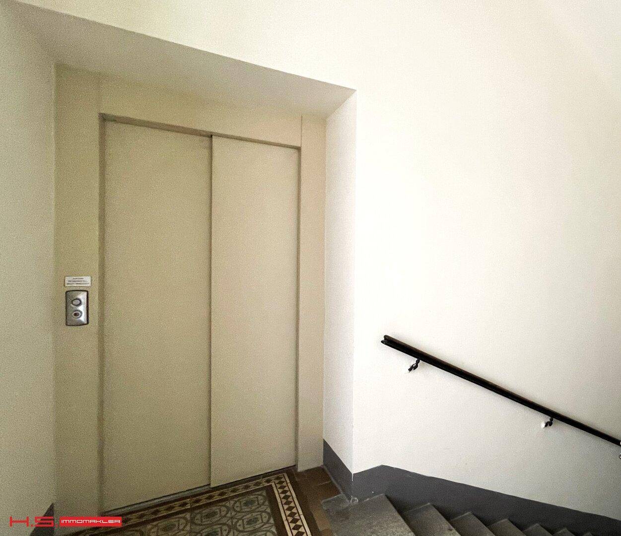 Eingangsbereich mit Aufzug und Treppenhaus, das den Zugang zu den oberen Etagen ermöglicht.