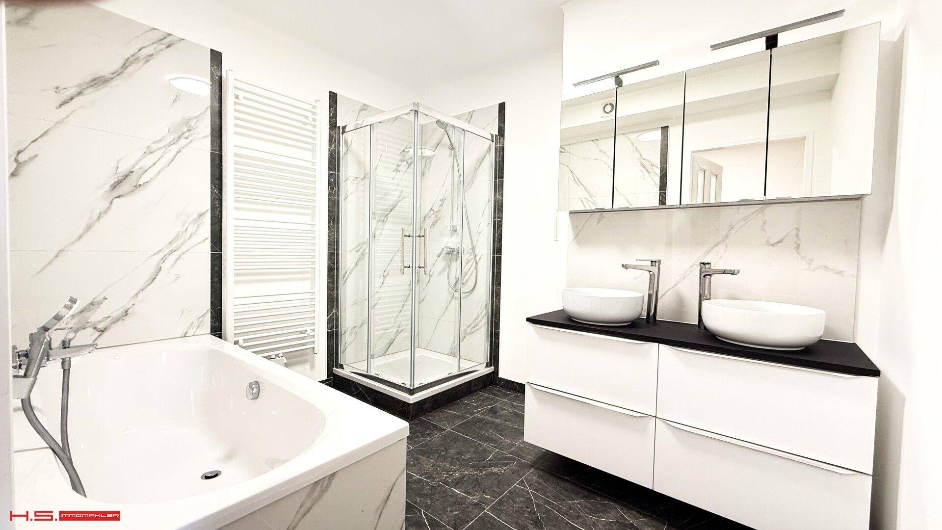 Modernes Badezimmer mit Badewanne, Duschkabine, Doppelwaschbecken und Marmorfliesen.