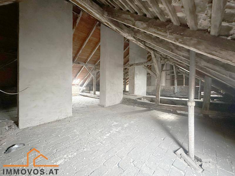 Weitläufiger Dachbodenbereich mit rustikalen Holzbalken und Ziegelboden, bietet viel Potenzial.