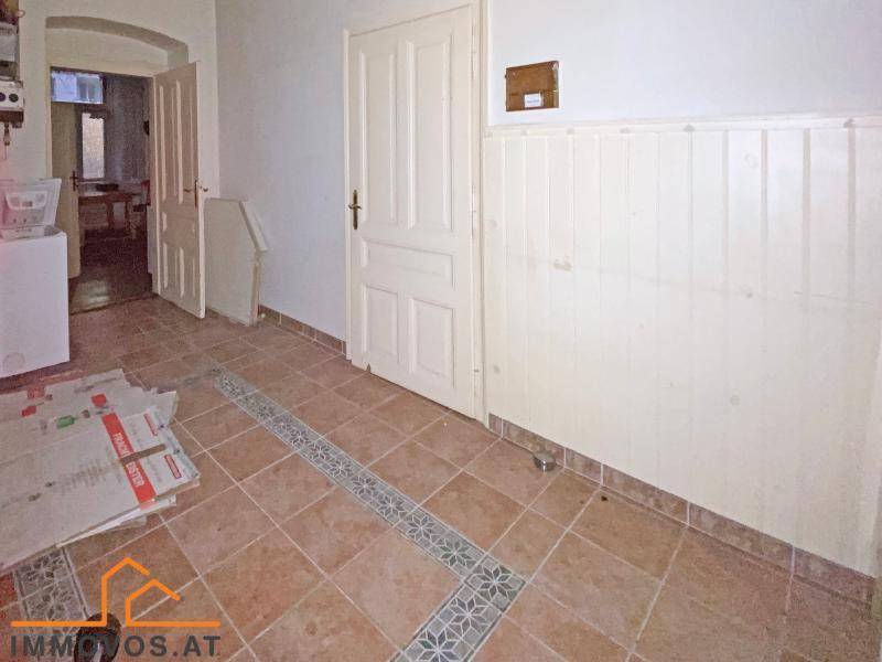 Flur mit Terrakotta-Fliesenboden, Holzvertäfelung und Zugang zu weiteren Räumen.