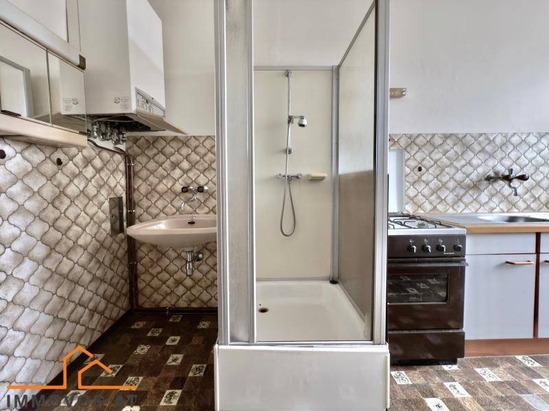 Funktionale Küche mit freistehender Duschkabine, Gasherd und Spülbecken.