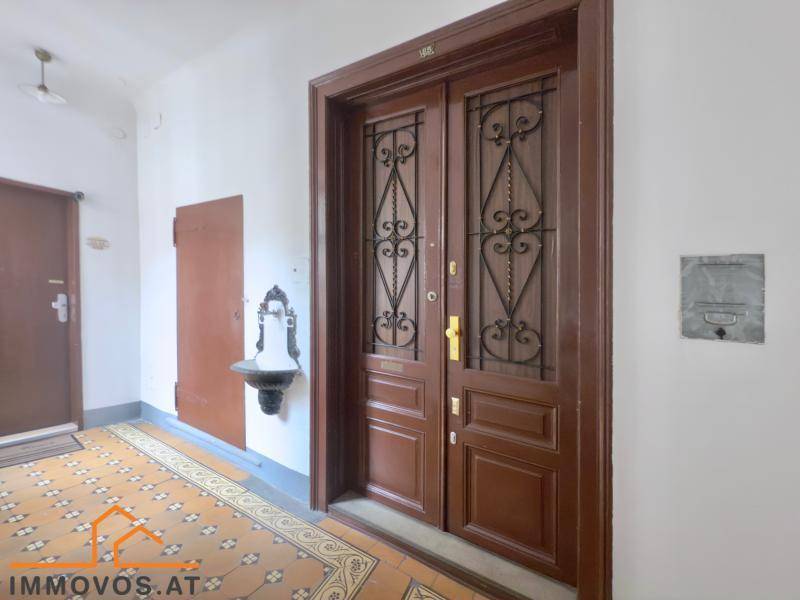 Historischer Hauseingang mit verzierten Holztüren und gemustertem Fliesenboden.