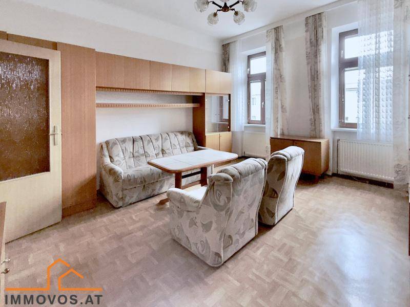 Helles Wohnzimmer mit Parkettboden, Schrankwand und bequemen Sitzmöbeln.