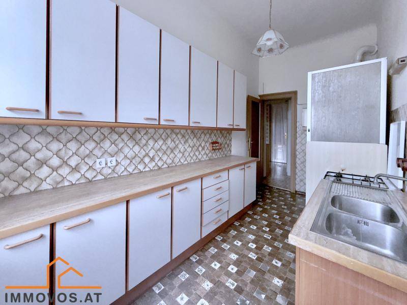 Geräumige Küche mit Gasherd, Doppelspüle und Zugang zu einem weiteren Raum.