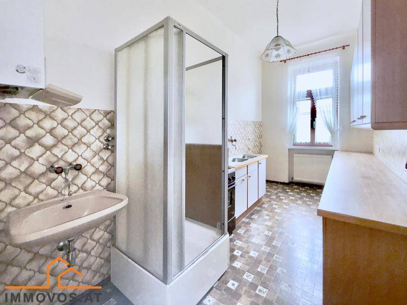 Ungewöhnliche Küche mit integrierter Duschkabine, Spülbecken und gemustertem Fliesenboden.