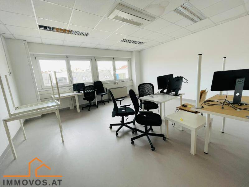Möbliertes Büro mit mehreren Arbeitsplätzen, Computern und großen Fenstern, ideal für ein Team.