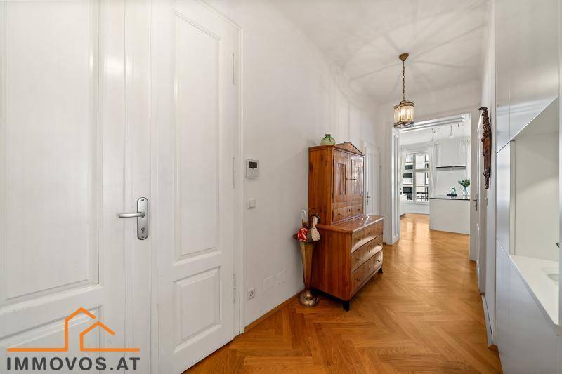 Heller Flur mit Fischgrätparkett, antiker Kommode und Zugang zu weiteren Räumen.