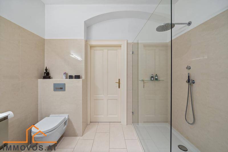 Helles Badezimmer mit begehbarer Dusche, Wand-WC und beigefarbenen Fliesen.