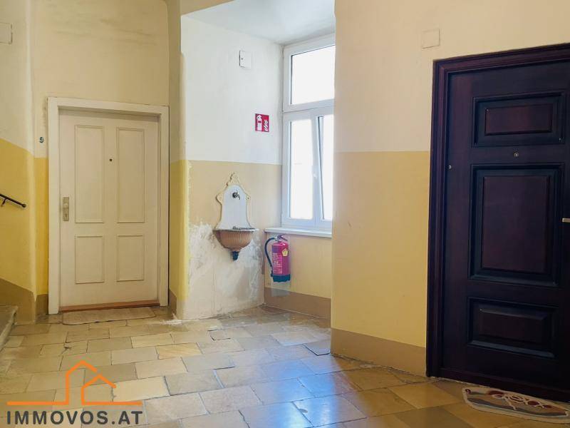 Historischer Hausflur mit alten Türen, Fenster und einem dekorativen Wandbrunnen.