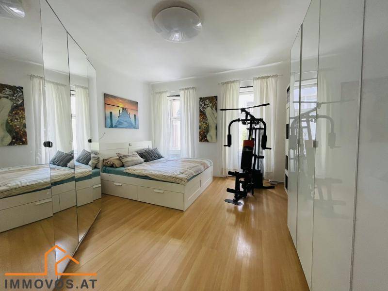 Helles Schlafzimmer mit Doppelbett, Spiegelschränken und Fitnessgerät.