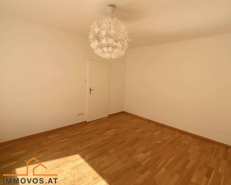 Leeres Zimmer mit hellem Parkettboden und einer modernen Deckenleuchte, bereit zur individuellen Gestaltung.