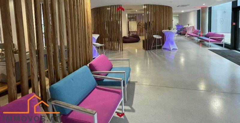 Stilvoller Loungebereich mit farbenfrohen Sitzmöbeln und dekorativen Holzlamellen als Raumteiler.