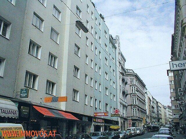 Mehrstöckiges Wohn- und Geschäftshaus in einer belebten Stadtstraße mit Geschäften im Erdgeschoss.