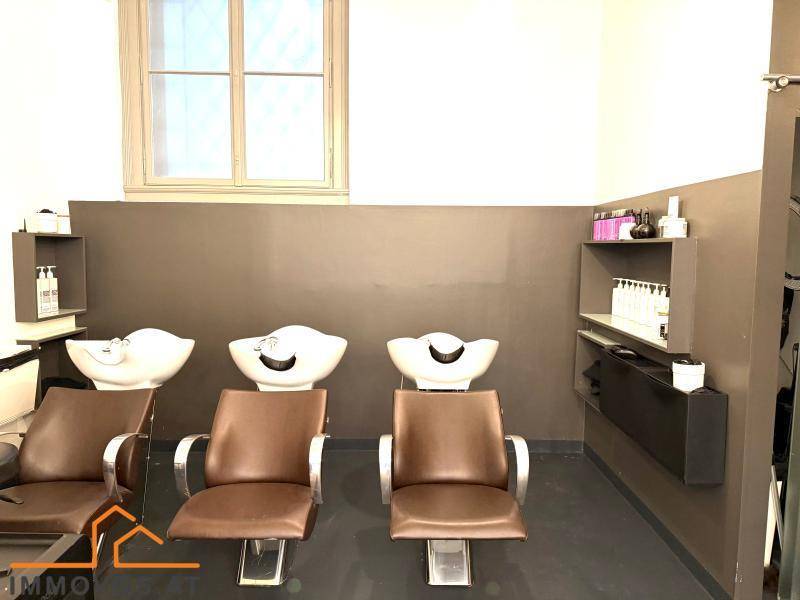 Haarwaschbereich in einem Friseursalon mit drei Waschbecken, bequemen Stühlen und einem Fenster.