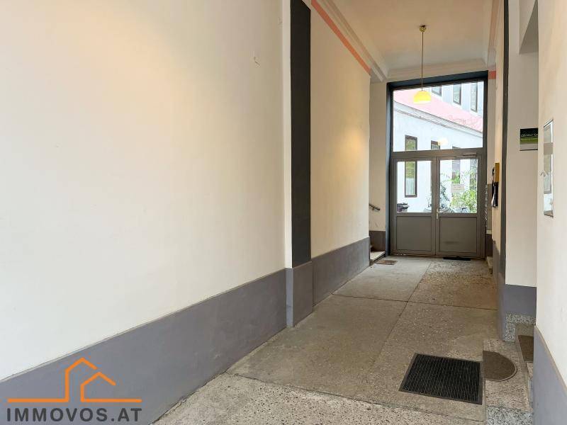 Eingangsbereich des Gebäudes mit Glastür zur Straße, der einen hellen Zugang bietet.