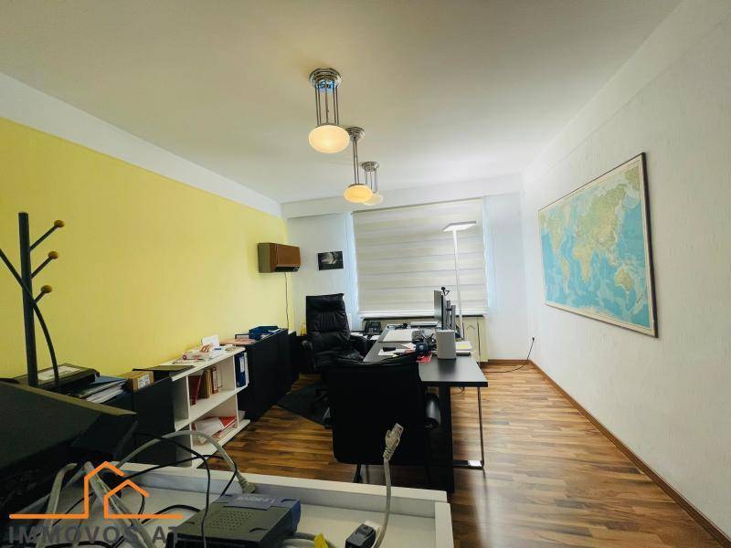 Büro mit mehreren Arbeitsplätzen, gelben Wänden und einer Weltkarte als Dekoration.