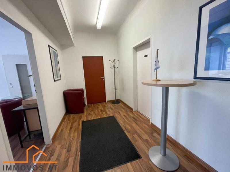 Heller Flur mit Holzboden, Stehtisch und Garderobe, der zu weiteren Räumen führt.