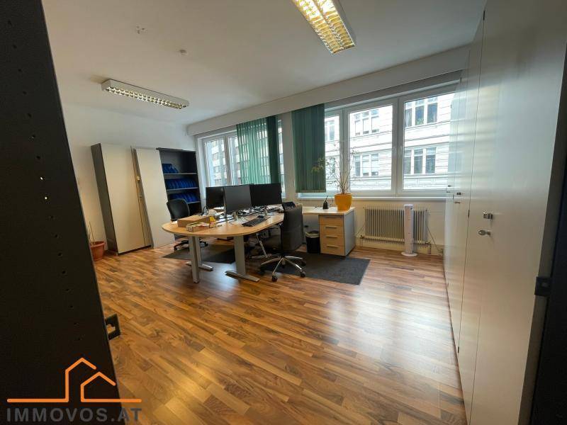 Helles Büro mit mehreren Arbeitsplätzen, großen Fenstern und integrierten Schränken für effiziente Nutzung.