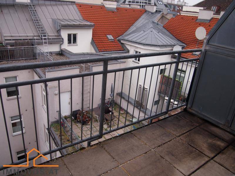 Dachterrasse mit Fliesenboden und Blick auf die umliegenden Dächer und einen Innenhof.