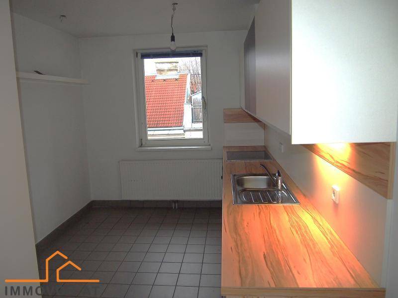 Küche mit Holz-Arbeitsplatte, Spüle und Fensterblick auf die Dächer.