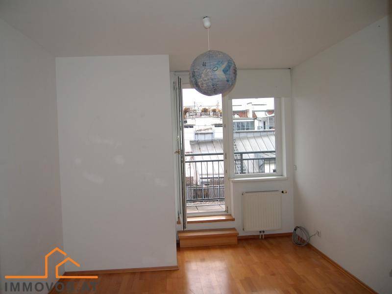 Heller Raum mit Holzboden und Zugang zu einem französischen Balkon mit Stadtblick.