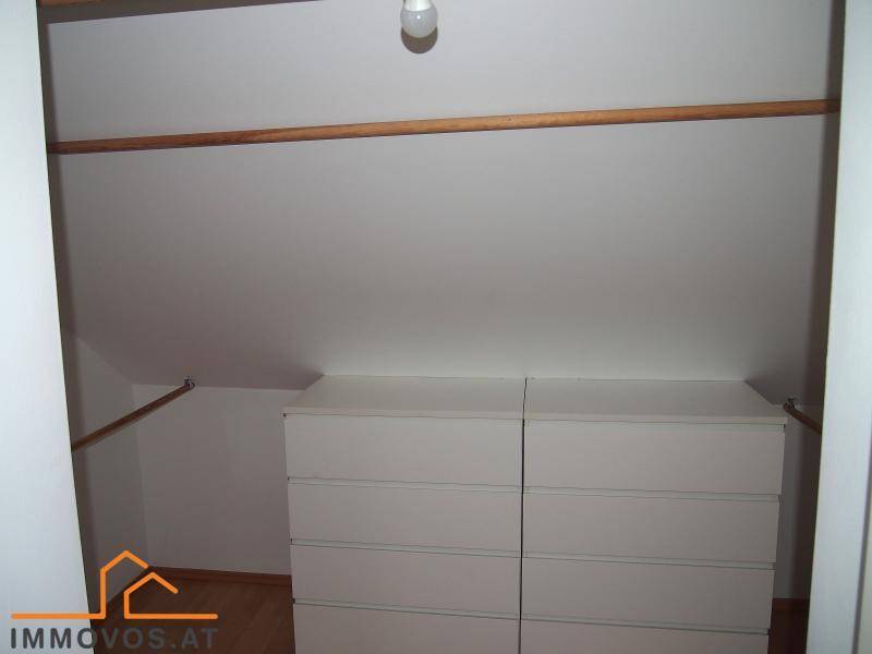 Begehbarer Kleiderschrank mit Stauraum und Kleiderstangen unter der Dachschräge.