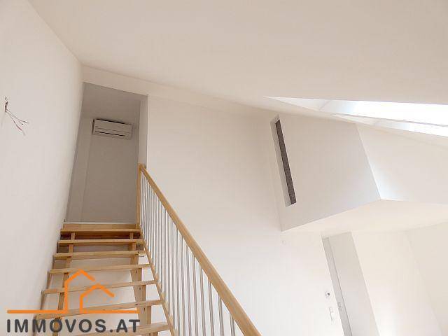 Treppenaufgang zu einem hellen Dachgeschossbereich mit Klimaanlage und Dachfenstern.