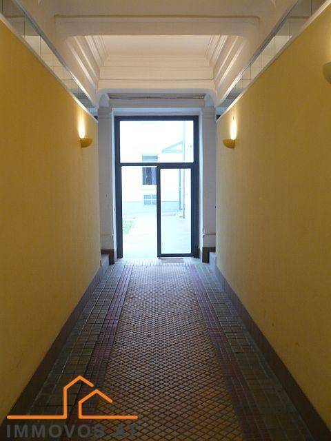 Heller Durchgangsbereich mit gelben Wänden und Zugang zum Innenhof.