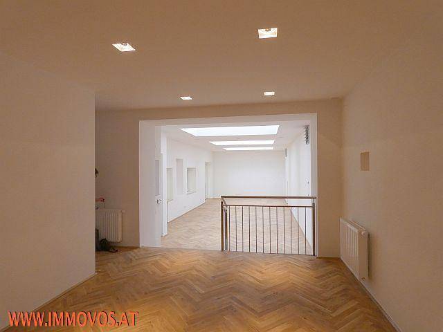 Heller, offener Wohnbereich mit Parkettboden und Blick auf den unteren Wohnbereich mit Dachfenstern.