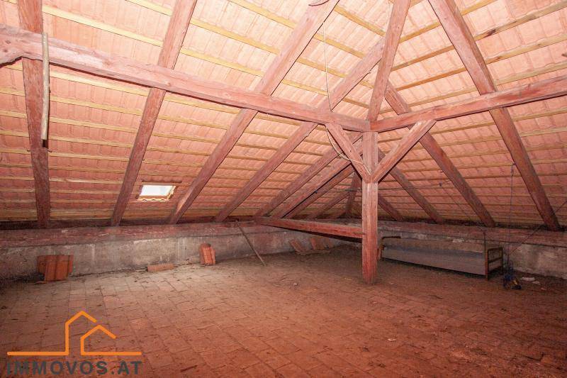 Geräumiger Dachboden mit sichtbaren Holzbalken und Ziegeln, ideal für einen zukünftigen Ausbau.