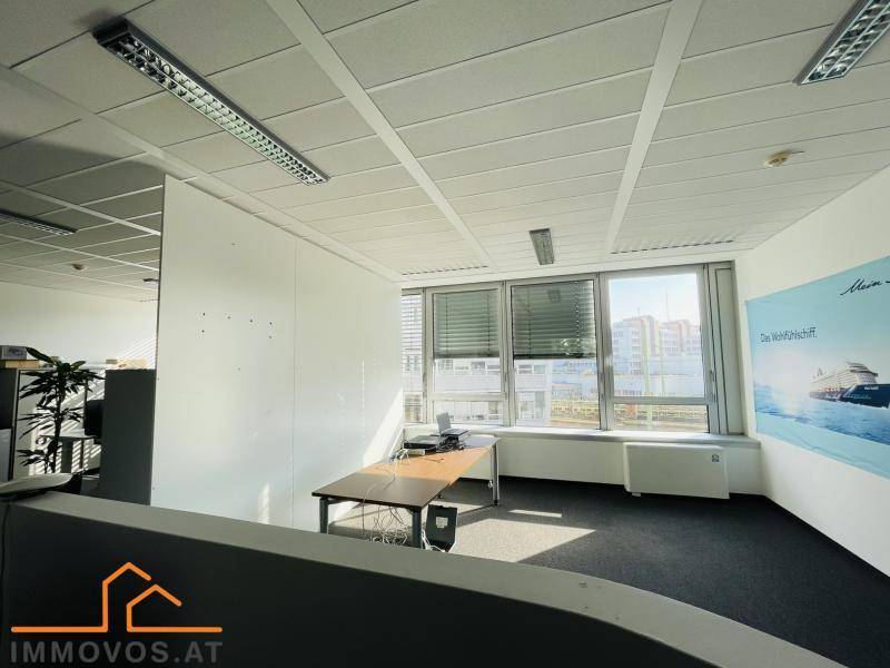 Helles Büro mit Schreibtisch, Stuhl und großen Fenstern, die viel Tageslicht hereinlassen.