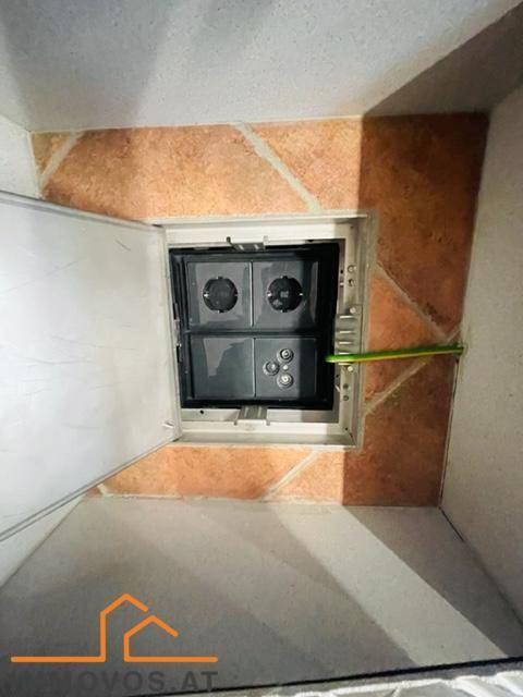 Detailansicht eines Elektroverteilerkastens in einer Wandnische mit Fliesenrahmen.