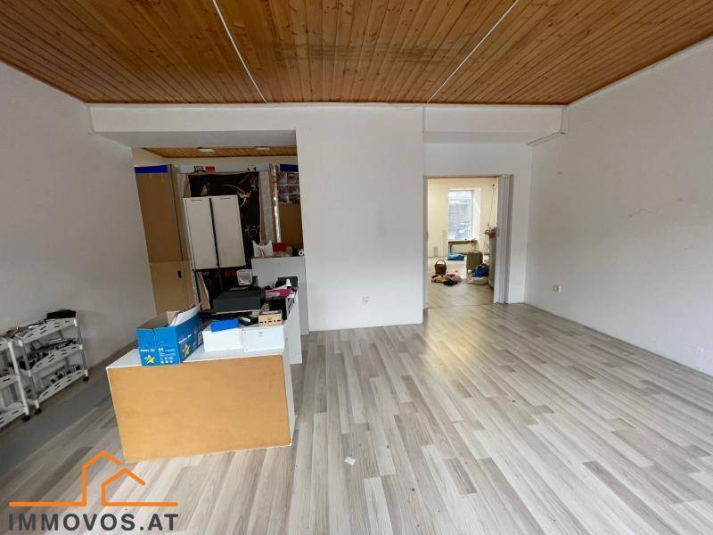Heller Gewerberaum mit Holzdecke und Laminatboden, der einen Einblick in einen angrenzenden Bereich gewährt.
