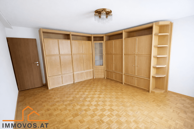 Geräumiges Zimmer mit Parkettboden und einer großen, hellen Einbauschrankwand.