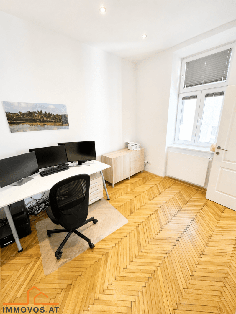 Arbeitszimmer mit Fischgrätparkett, Schreibtisch und Fenster mit Jalousien, bietet eine ruhige Arbeitsumgebung.