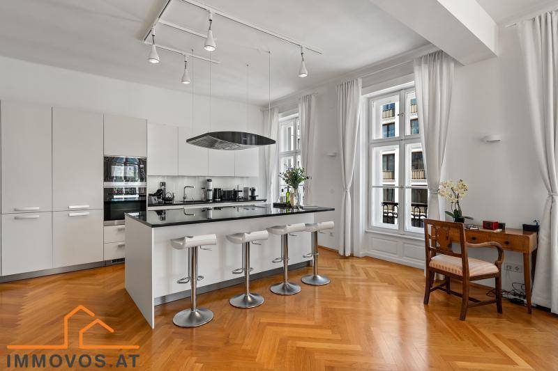 Moderne weiße Küche mit Kochinsel, Barhockern und Fischgrätparkett in hellem Ambiente.