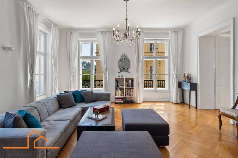 Elegantes Wohnzimmer mit großem Ecksofa, Fischgrätparkett und hohen Fenstern.