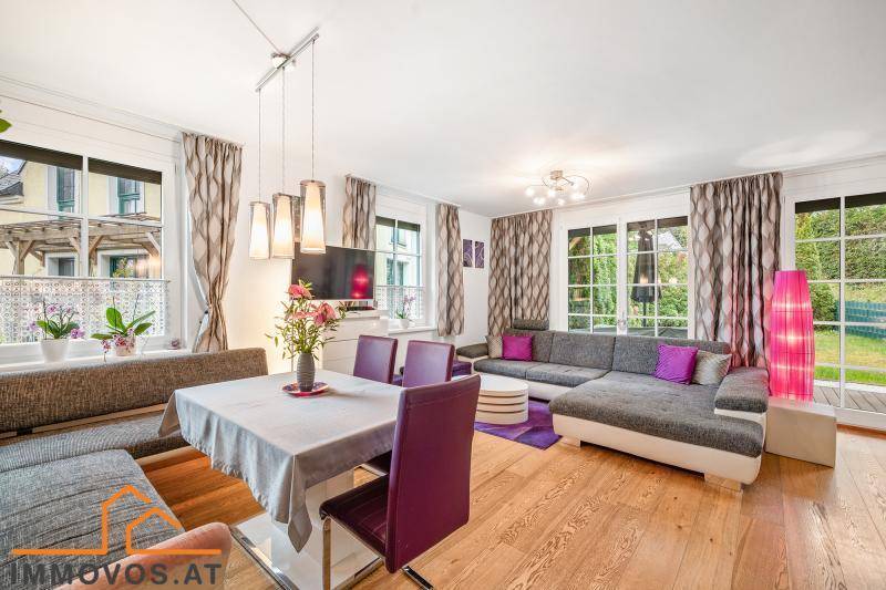 Lichtdurchfluteter Wohn-Essbereich mit Eichenparkett, gemütlichem Sofa und Blick ins Grüne.