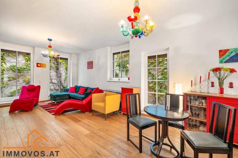 Farbenfrohes Wohnzimmer mit Holzboden, modernen Möbeln und Blick ins Grüne.